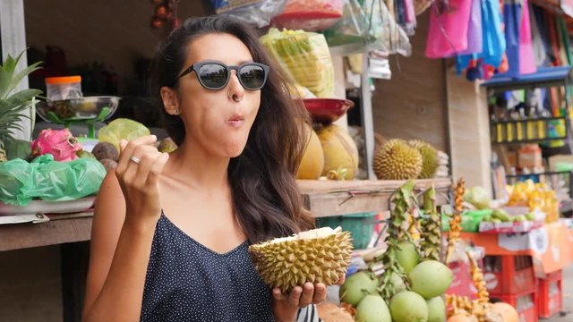 Young Mixed Race Tourist Woman Eating Exotic Durian Fruit. 4K, Bali, Indonesia.