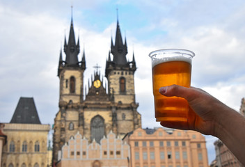 Obraz premium Man hand showing beer glass over Prague cityscape