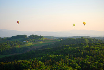 Fototapeta premium Ballonfahren Drei Heißluft-Ballons schweben über die oststeirische Hügellandschaft. 