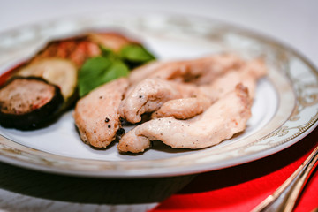 Pieces of roasted chicken and vegetables on plate