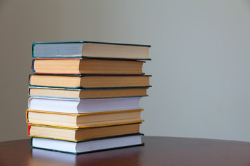 a stack of books on a wooden old table and a light background