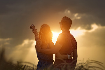 Silhouettes of a couple in the field watching the sunset / sunrise.