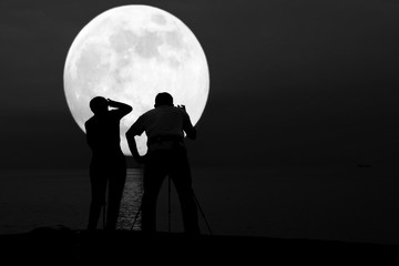 Silhouette of couple taking photo of super blue moon