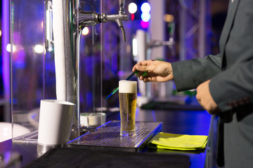 Waiter with glass of  beer in pub at night