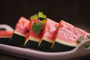 Fresh sliced watermelon in white dish on wooden table.