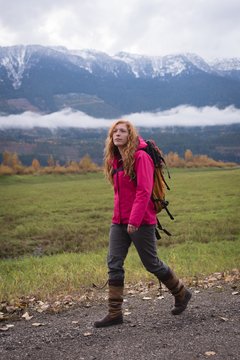 Woman walking on a dirt track against snow clad mountain and
