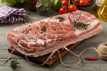 Raw bacon in whole on wooden background.