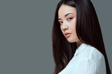 close-up portrait of beautiful asian girl looking at camera isolated on grey