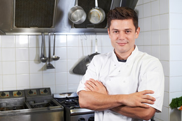 Portrait Of Chef Wearing Whites Standing By Cooker In Kitchen