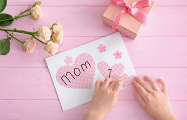 Little girl preparing greeting card for her mommy on Mother's Day at table