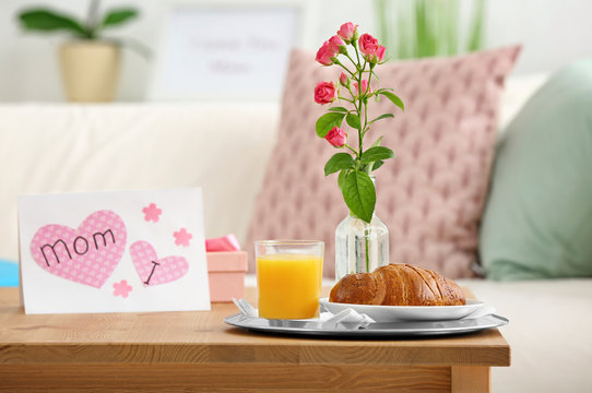 Yummy breakfast, flowers and card as greetings for Mother's Day on table indoors