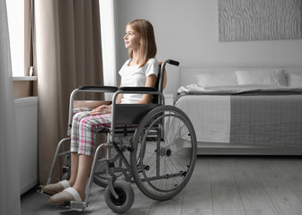Teenage girl in wheelchair near window indoors