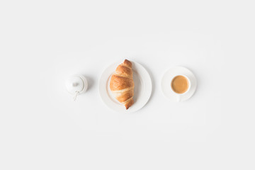 top view of cup of coffee and croissant for breakfast on white surface