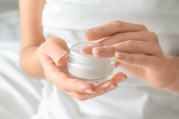 Woman with jar of hand cream at home, closeup