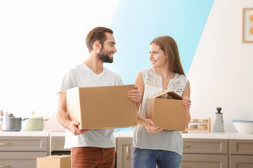 Young couple with moving boxes in kitchen at new home