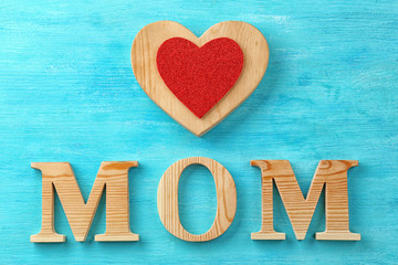 Word "Mom" and heart figure on wooden background. Mother's day celebration