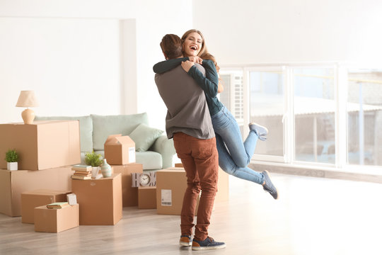 Young happy couple in room with moving boxes at new home