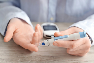 Woman using lancet pen, closeup. Diabetes monitoring