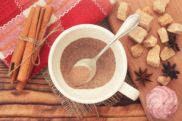 Top view dry cacao powder in cup with cane sugar and anise cinnamon condiment