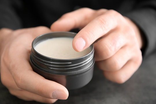 Man holding jar with clay for hair, closeup