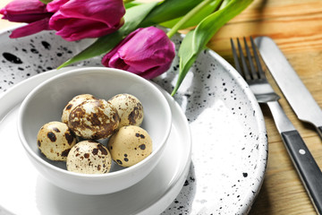 Beautiful festive Easter table setting with quail eggs and tulips, closeup