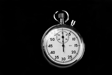 Old stopwatch isolated on black background top view