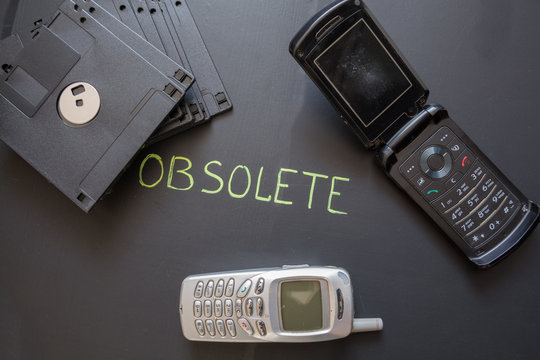 Old mobile phones and floppy disks on dark background.