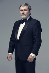 Middle aged male adult wearing a suit isolated on gray