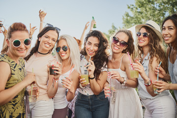 Group of people standing and drinking at the summer outdoor party 