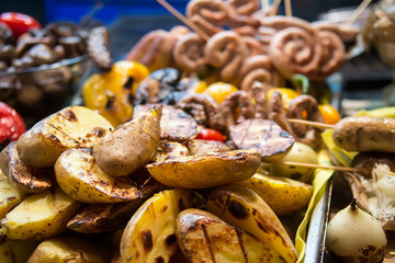 Grilled potatoes and fried sausages on outdoor market stall
