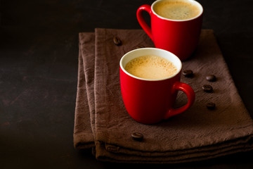 Two red cups of espresso on dark wooden background decorated coffee beans