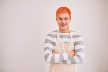 Happy and confident male cafe worker in apron smiling at a camera, standing.