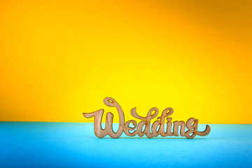 Wedding inscription on blue and yellow background. Wooden letters.
