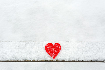 Red heart on the snow wooden plank. Valentne's day concept.