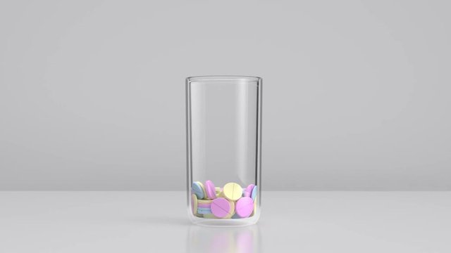 Bunte Tabletten - Pillen fallen in ein Glas