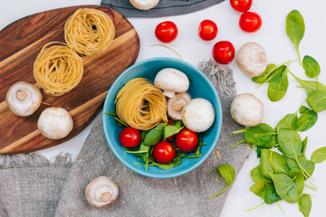 Fresh spinach and cherry tomatoes with mushrooms and pasta. Raw vegetable. natural plant leaf. healthy and vegetarian or organic bio food. top view. close up