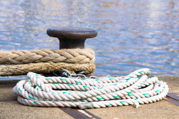 Fototapeta na wymiar Ship mooring ropes secured around a port bollard