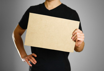 A young guy in a black t-shirt holding a piece of cardboard. Prepared for your text