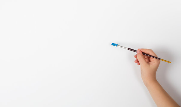 Child hand holding a paint brush on white background