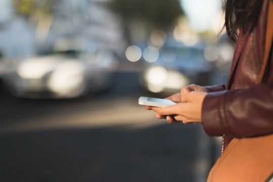 Woman using mobile phone in city street