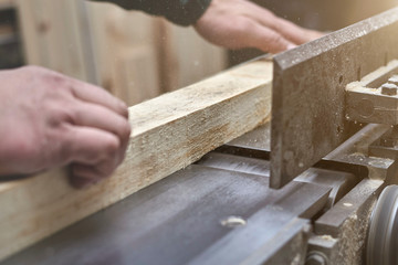 the man processes bar from a light tree on the jointer plane