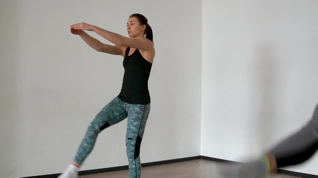 Two female athletes in a sport dress perform a step-up raising of their legs. Stretching and paletes are performed by a professional instructor in a personal lesson. Close-up, the camera is moving