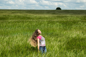 Fototapeta premium A girl in a field of rye on a summer day.