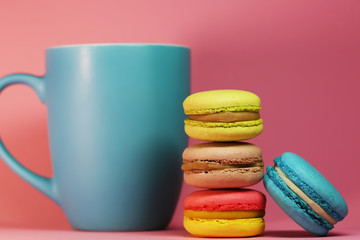 Blue tea cup on pink background with macaroons