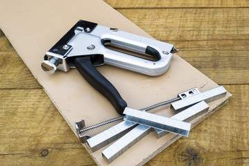 A construction stapler on a wooden background.