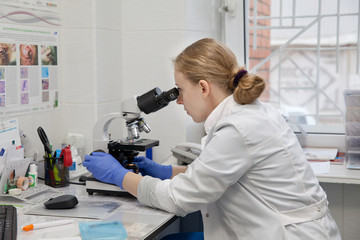 Doctor woman working with a microscope in Laboratory. Female scientist looking through a microscope in lab. Scientist using a microscope in a laboratory.