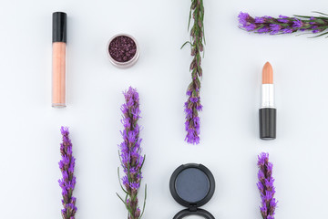 Eye shadow glitter set, blue eye shadow and nude orange lipstick decorated with violet liatris flowers on white background 