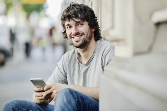 Portrait of smiling young man with cell phone outdoors