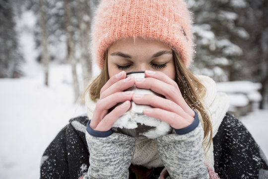Young woman enjoying hot drink outdoors in winter