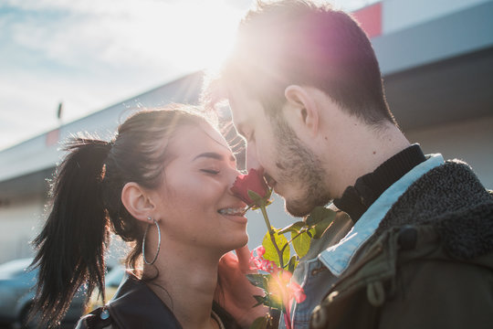 Young attractive couple are going to kiss at Valentines day with rose between them.